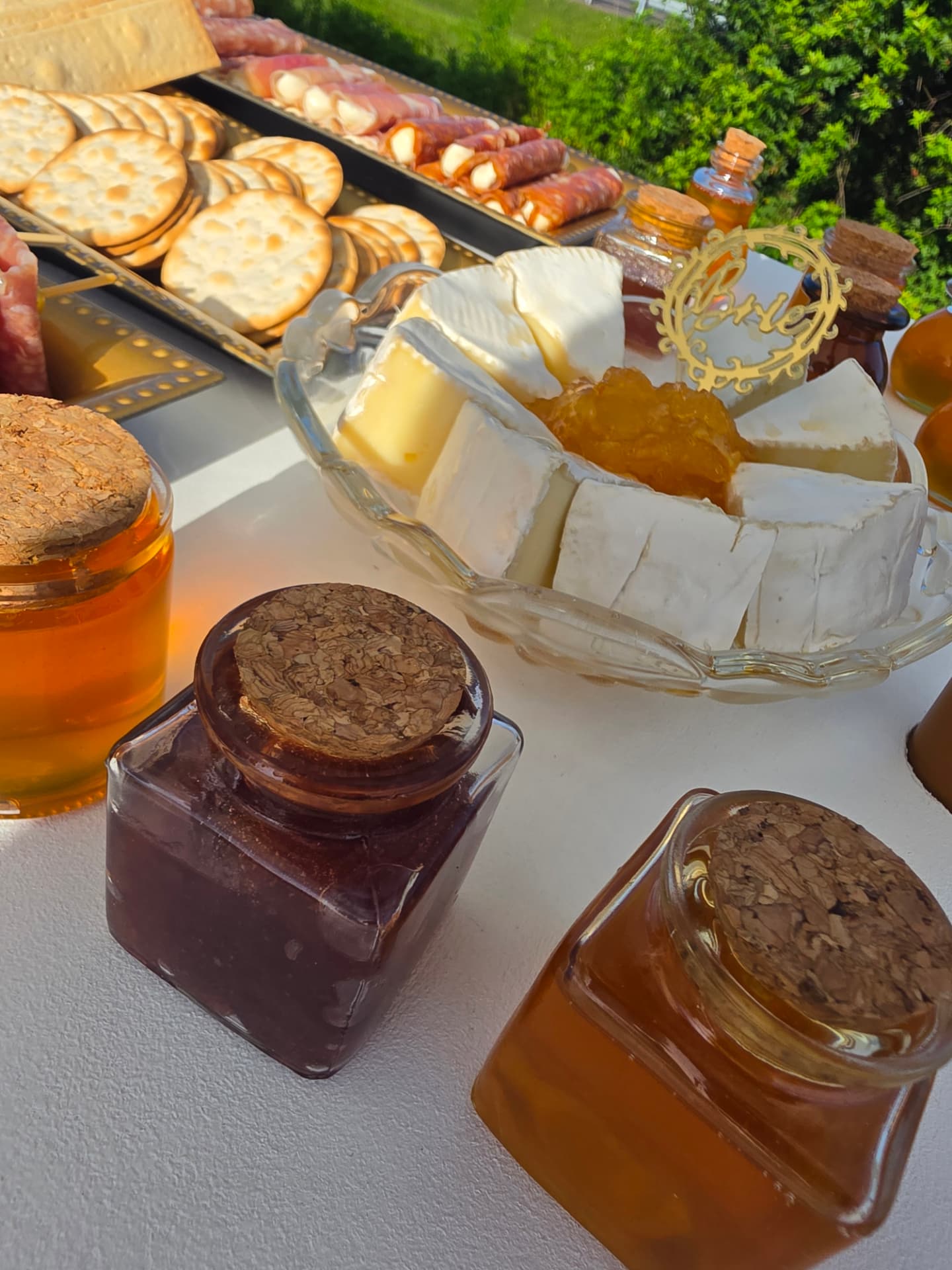 Brie with fruit preserve surrounded by honey and jam jars