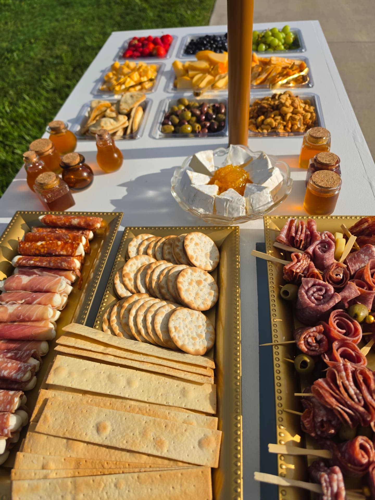 Estate table with gold trays of cured meats, crackers, cheeses and honey jars